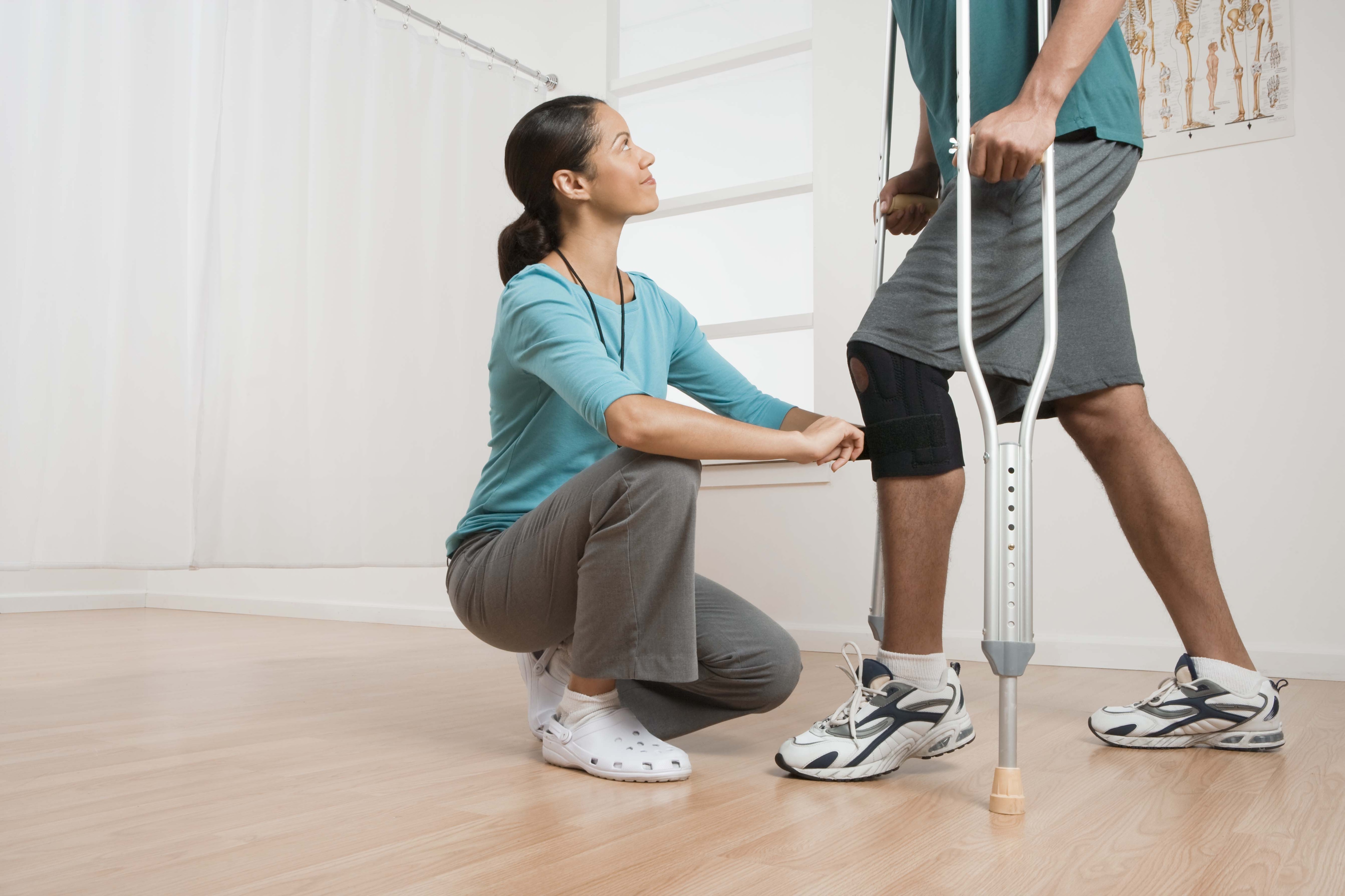 Physical therapist helping patient with crutches